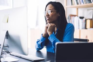 A smiling woman watching webinar on computer