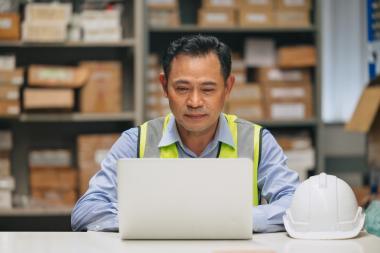 A logistics worker looking at a laptop in their warehouse